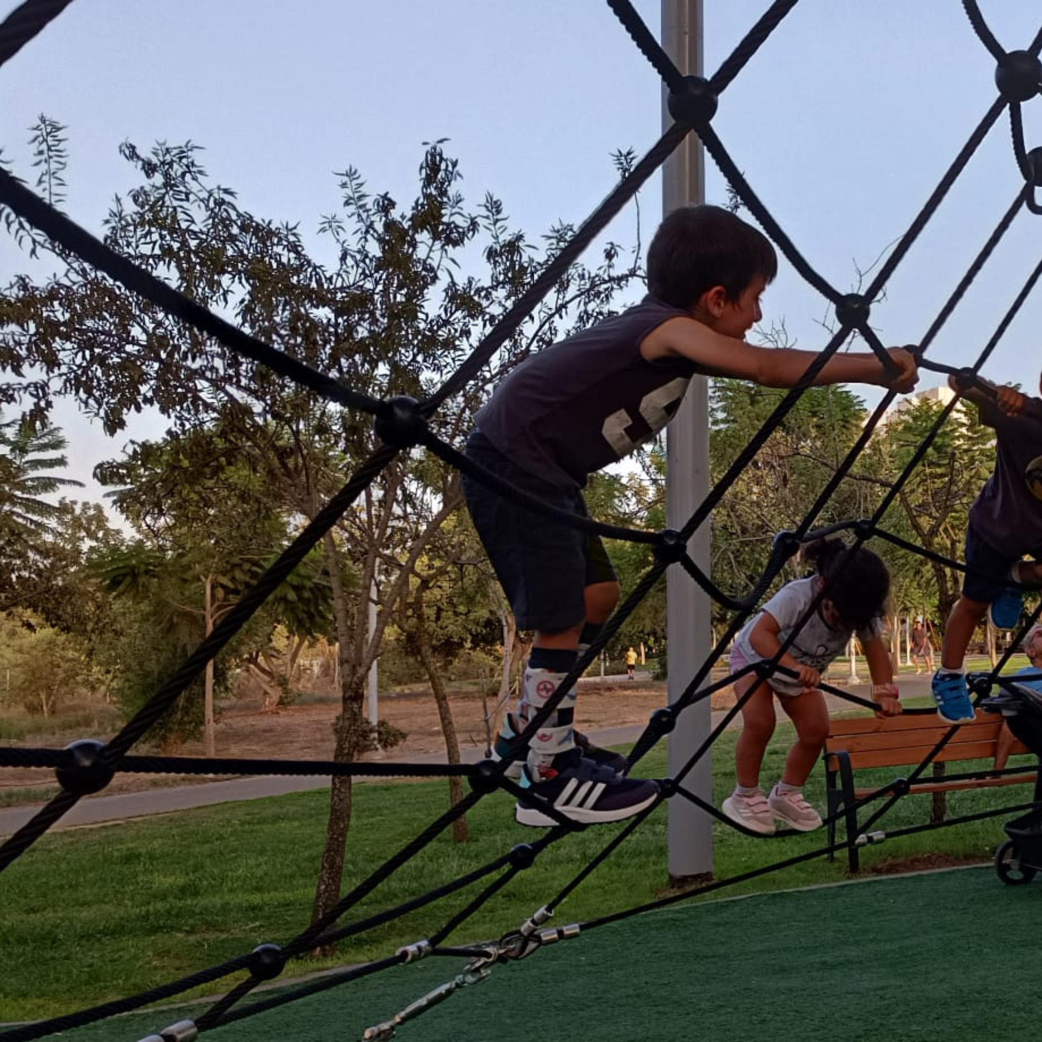 Kids wearing Lairos AFO socks climb a playground net outdoors, showcasing comfort and support.