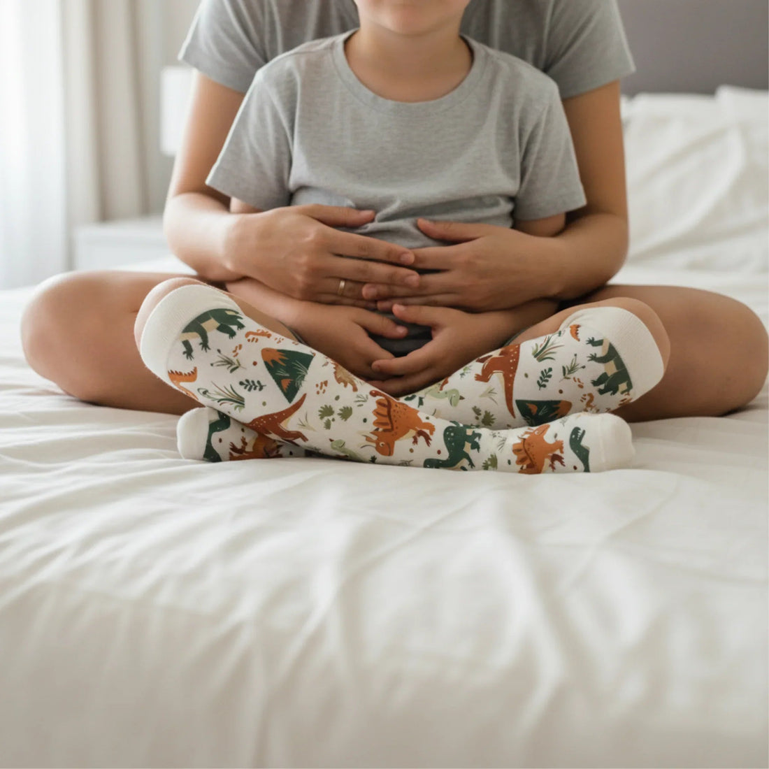 A person sitting cross-legged on a bed wearing Lairos' patterned seamless AFO socks.